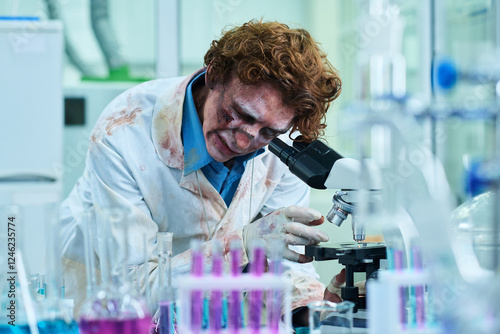 Male Zombie Technician in Blood-Stained Coat Working in Chemical Lab photo