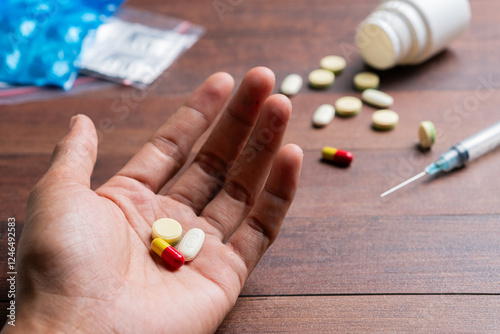 Hand Holding Pills with Syringe on Wooden Surface