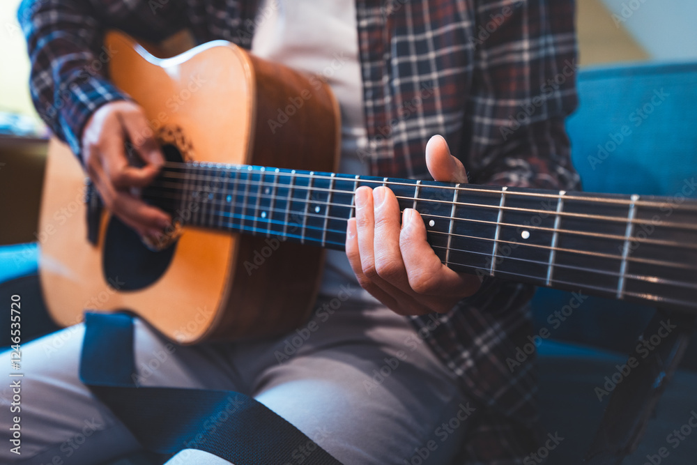 Fototapeta premium Close-up of a musician playing an acoustic guitar, fingers pressing on the fretboard, evoking a sense of creativity, passion, and emotional connection through warm, resonant tones