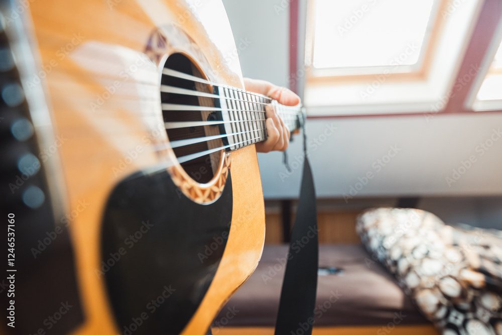 Fototapeta premium Close-up perspective of an acoustic guitar being played, with fingers pressing the fretboard, capturing the warmth of natural wood, the resonance of the strings. Indoor music