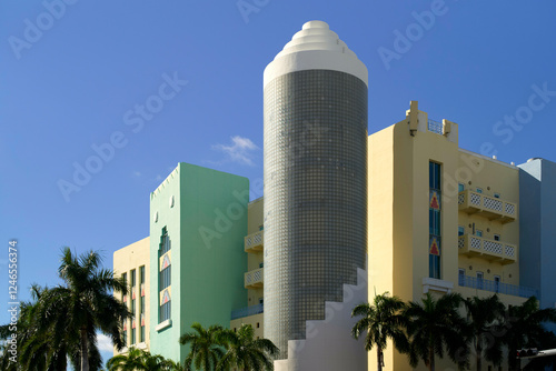 Colorful Art Deco building with a cylindrical glass block tower and palm trees under a blue sky, Miami, Florida, USA