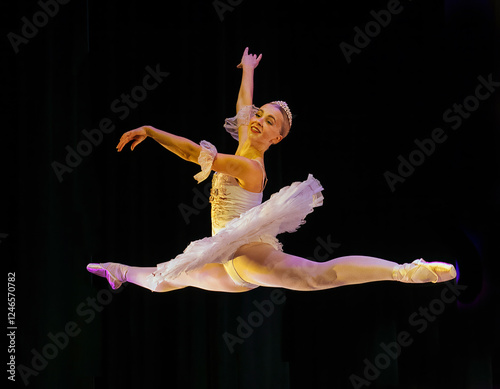 Ballerina in a white tutu performing a grand jetÈ on stage with dramatic lighting. The Nutcracker, Bainbridge Island, USA photo