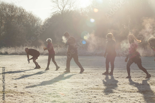 A group of people engaged in outdoor exercise in a frosty field, with sunlight creating lens flares and mist visible from their breath. Sale Water Park, Manchester, UK photo