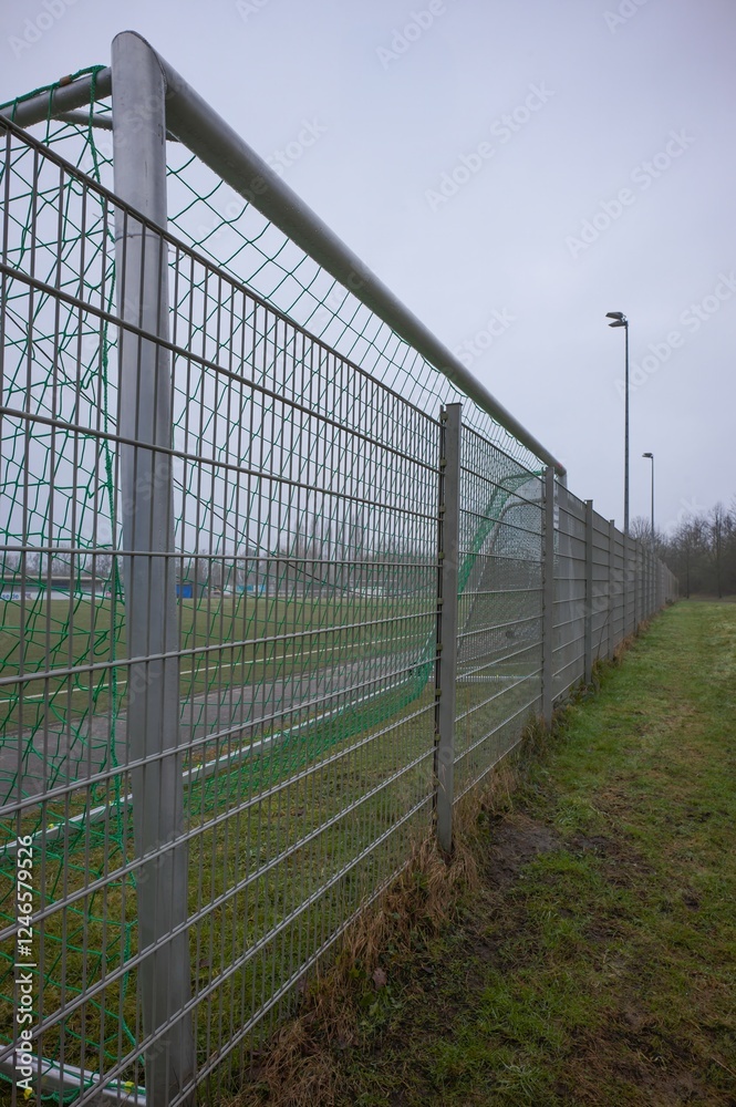 Metal fence surrounding soccer field on cloudy day Metal fence surrounding soccer field on cloudy day