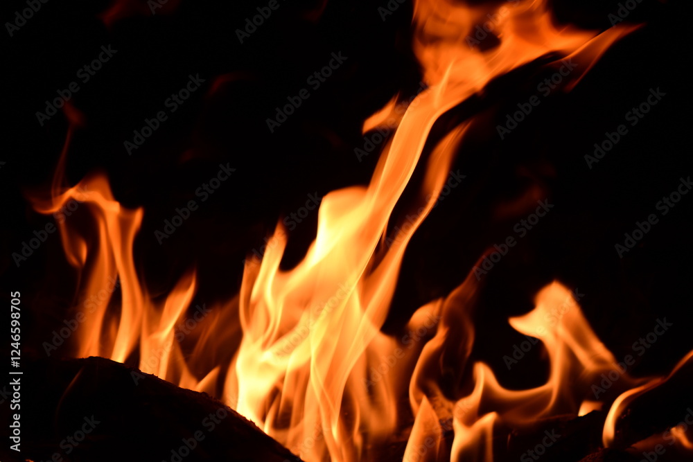 Fire flames on a black background. Burning firewood in the fireplace, close-up Fire flames on a black background. Burning firewood in the fireplace, close-up