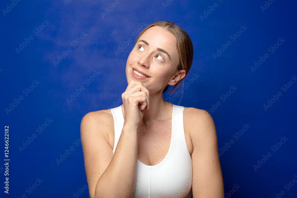 blonde woman smiling happily and daydreaming or doubting, looking to the side blonde woman smiling happily and daydreaming or doubting, looking to the side