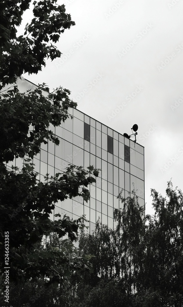 Obraz premium Modern building facade seen through trees, monochrome urban scene