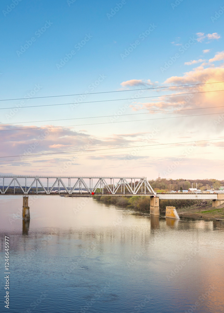 Fototapeta premium Bridge spans a river with a beautiful sunset in the background