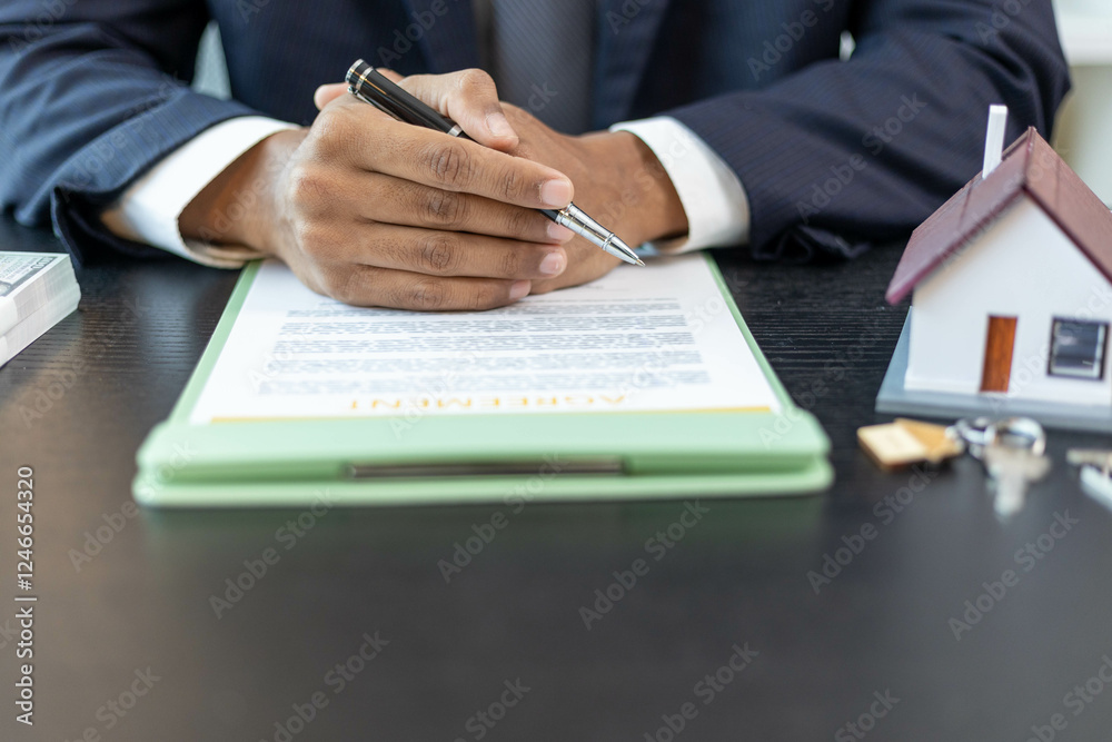 A man is signing a contract on a table with a house and a calculator. Scene is serious and professional
A man is signing a contract on a table with a house and a calculator. Scene is serious and professional