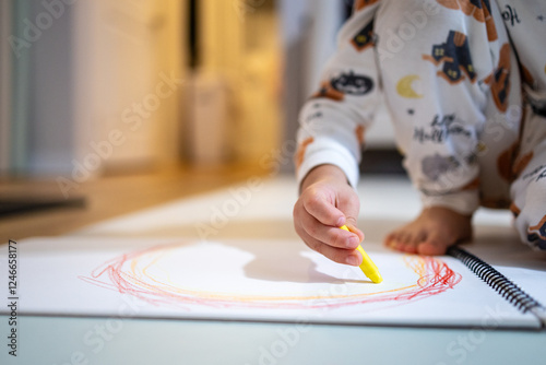 Child is drawing a circle with a yellow crayon