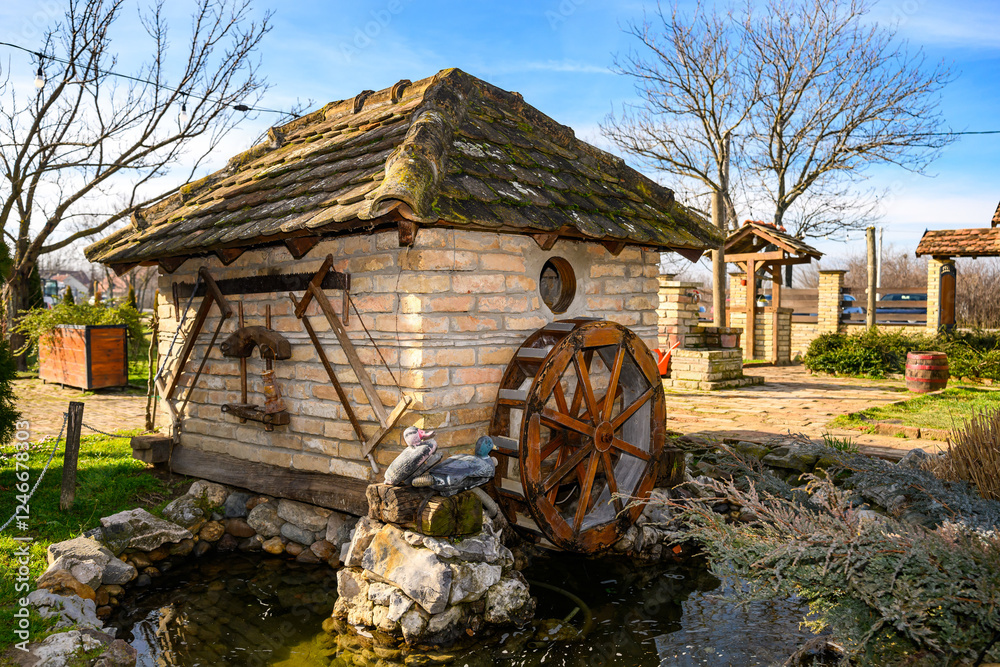 Novi Sad, Serbia- January 26, 2025: Vojvodina farm (Serbian; Vojvodjanski Salaš) a beautiful restaurant near Novi Sad. Decorated small watermill. Decorative water wheel in the garden