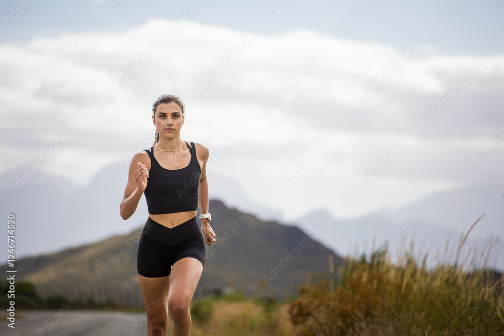 Female athlete in black sportswear running on a rural road with a scenic mountainous backdrop, emphasizing endurance and outdoor fitness. Female athlete in black sportswear running on a rural road with a scenic mountainous backdrop, emphasizing endurance and outdoor fitness.