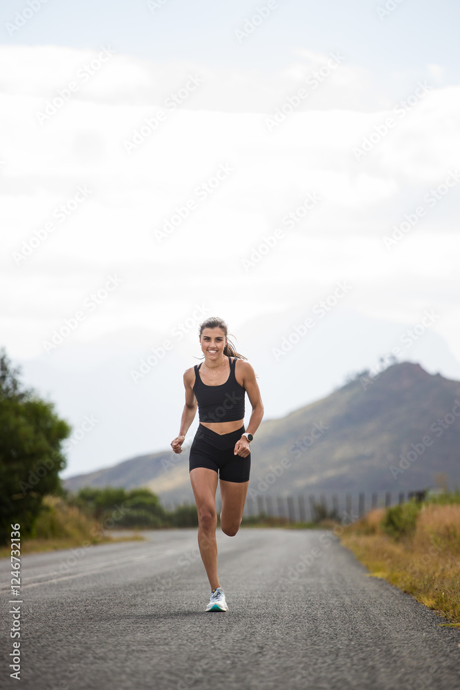 Female athlete in black sportswear running on a rural road with a scenic mountainous backdrop, emphasizing endurance and outdoor fitness. Female athlete in black sportswear running on a rural road with a scenic mountainous backdrop, emphasizing endurance and outdoor fitness.
