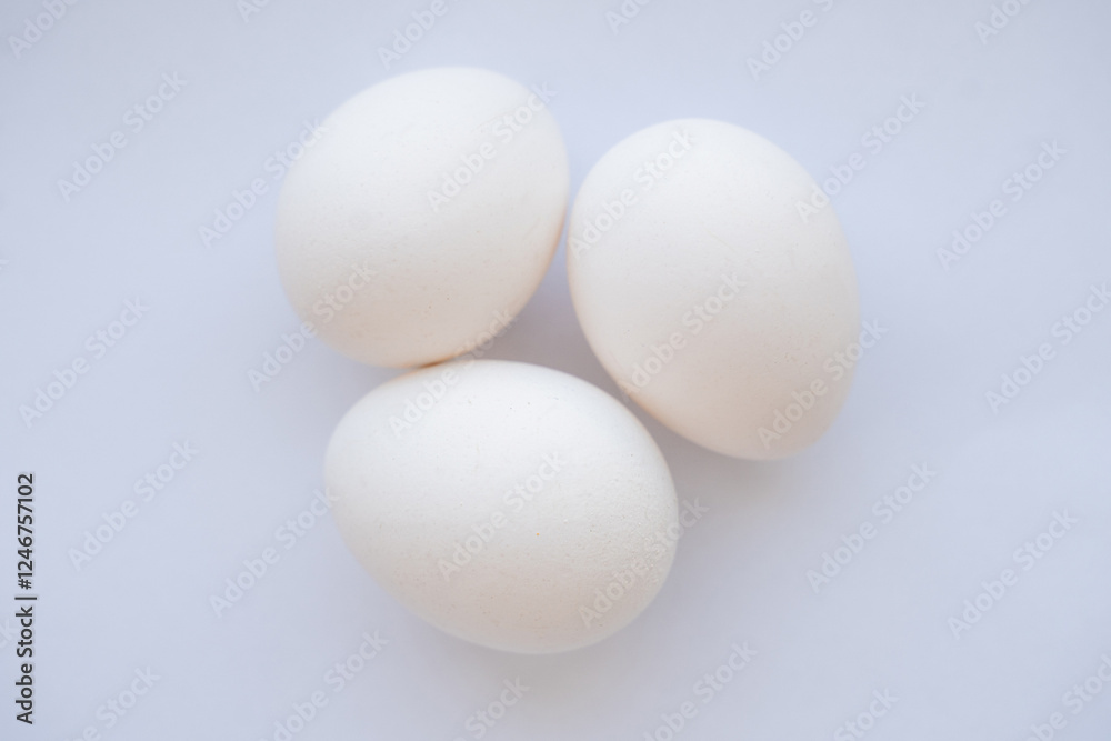 three white chicken eggs on a white background