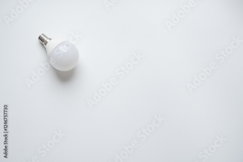 white opaque light bulb with narrow base lies on white background
