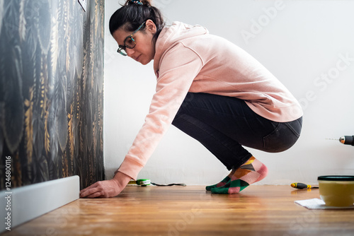 Фотография Woman installing baseboard in home renovation project