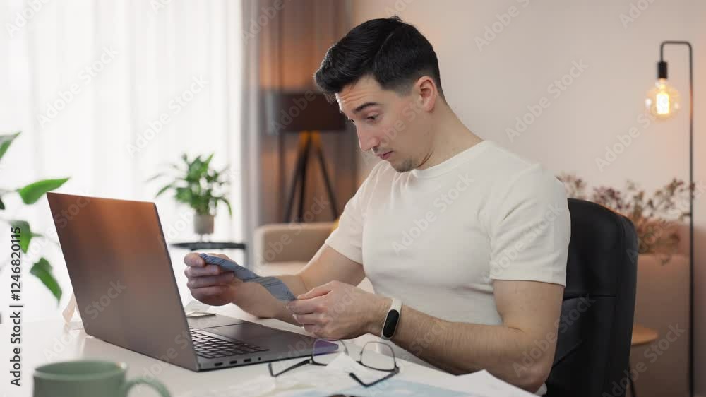 Tax time focus as a man puts on his glasses to examine a bill closely, working from home with documents spread around. Balancing finances and concentration in a warm, personal workspace Tax time focus as a man puts on his glasses to examine a bill closely, working from home with documents spread around. Balancing finances and concentration in a warm, personal workspace