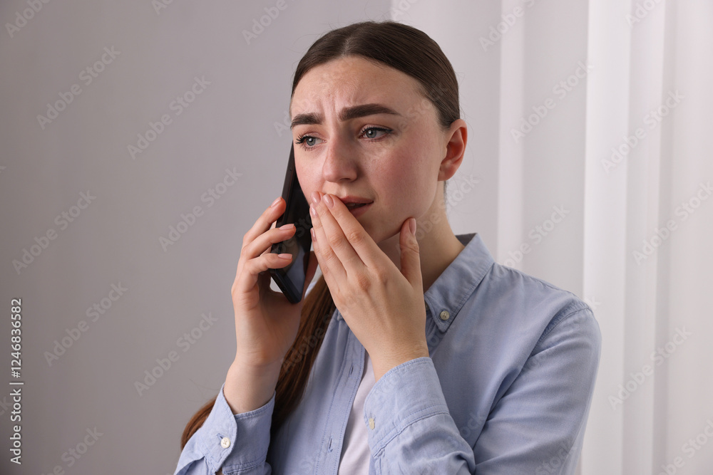 Stressed woman calling hotline for mental health help near window at home Stressed woman calling hotline for mental health help near window at home