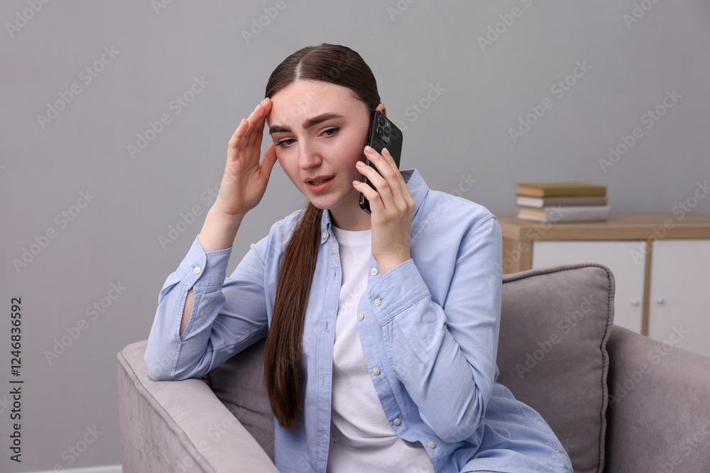 Stressed woman calling hotline for mental health help in armchair at home Stressed woman calling hotline for mental health help in armchair at home