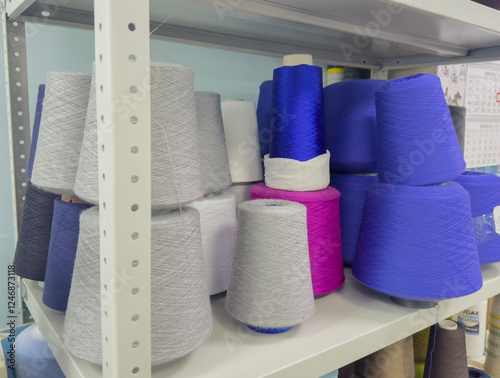Multi-colored yarn bobbins on the shelves of a warehouse for the production of textile projects