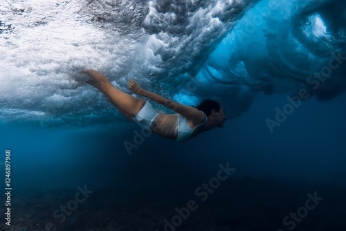 Woman duck dive with out surfboard under breaking ocean wave. photo