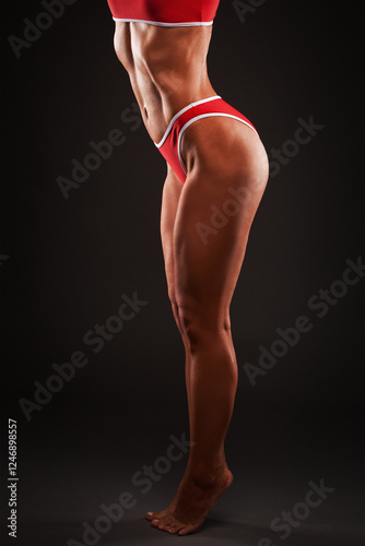 A slender swarthy Bodybuilder girl in red sportswear on a black background. Healthy lifestyle, sport and diet. photo