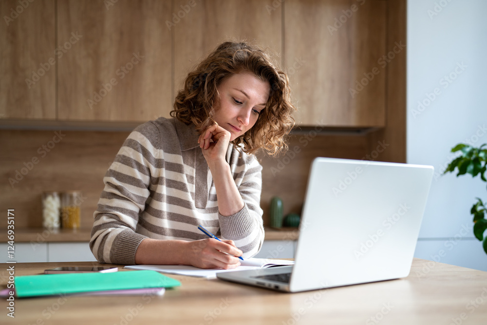 Focused student girl studying at home, sitting at kitchen table with laptop, writing notes in notebook. Serious young woman deep in thought engaged in online learning, self-education, exam preparation Focused student girl studying at home, sitting at kitchen table with laptop, writing notes in notebook. Serious young woman deep in thought engaged in online learning, self-education, exam preparation