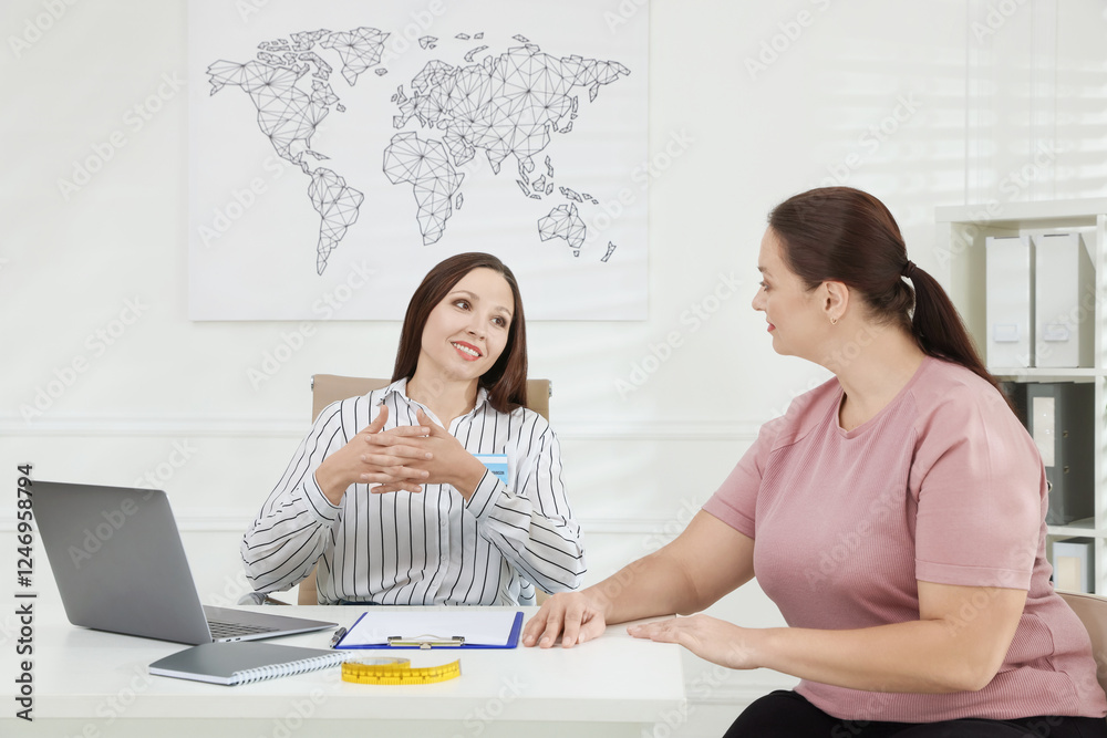 Overweight woman having consultation with nutritionist at desk in clinic Overweight woman having consultation with nutritionist at desk in clinic