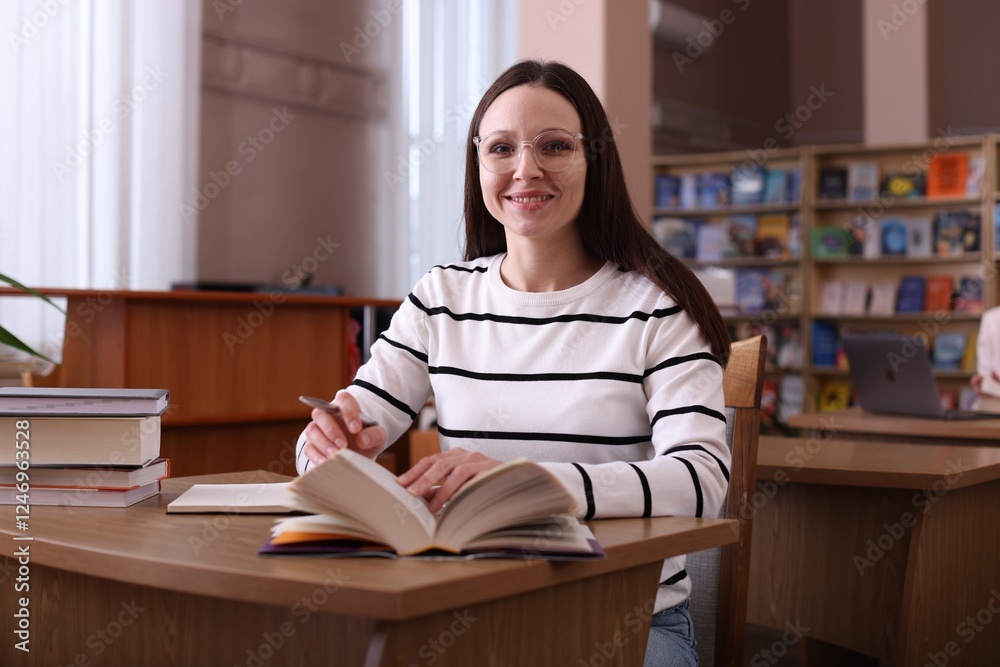 Portrait of smiling woman with books at desk in public library Portrait of smiling woman with books at desk in public library