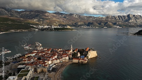 Stunning aerial view of the old European city, located on the seashore, surrounded by majestic mountains. Sky with impressive wavy clouds.
