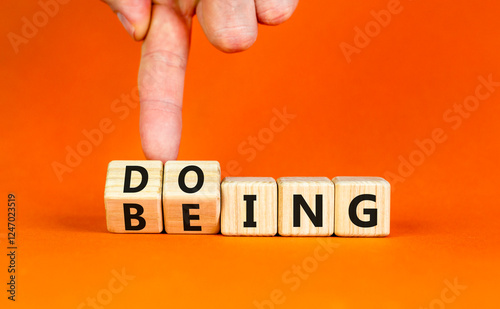 Doing or being symbol. Concept word Doing and Being on wooden cubes. Businessman hand. Beautiful orange table orange background. Business doing or being concept. Copy space.