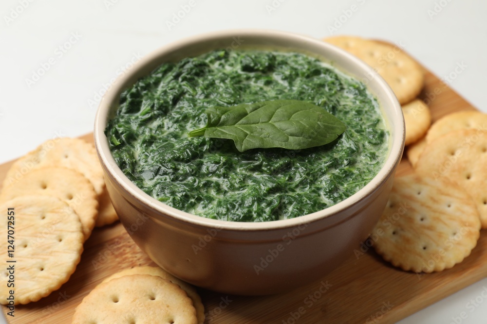 Delicious spinach sauce in bowl and crackers on table, closeup Delicious spinach sauce in bowl and crackers on table, closeup