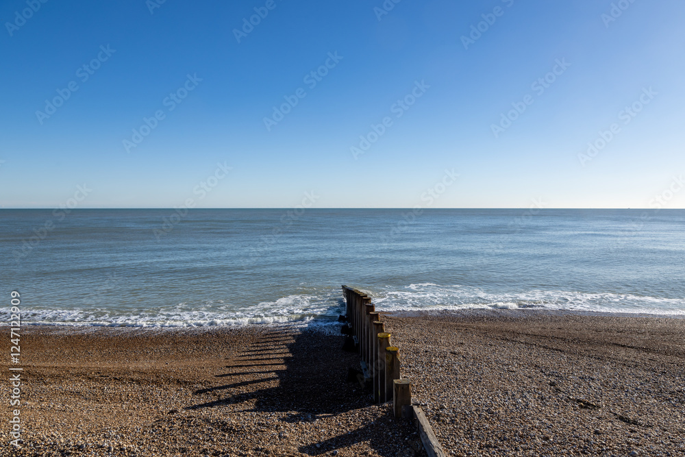 Φωτογραφία A wooden groyne on the pebble beach at Eastbourne, with a blue sky overhead