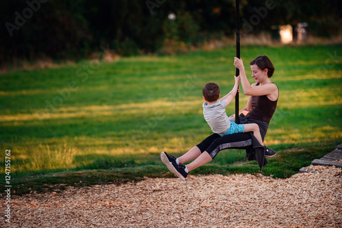 Woman and boy sharing a zip line ride at the playground