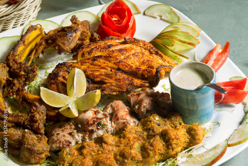 BBQ Platter on a white plate and fresh salad dressing | Platter with grilled chicken piece, kabab, boti, mutton chops photo