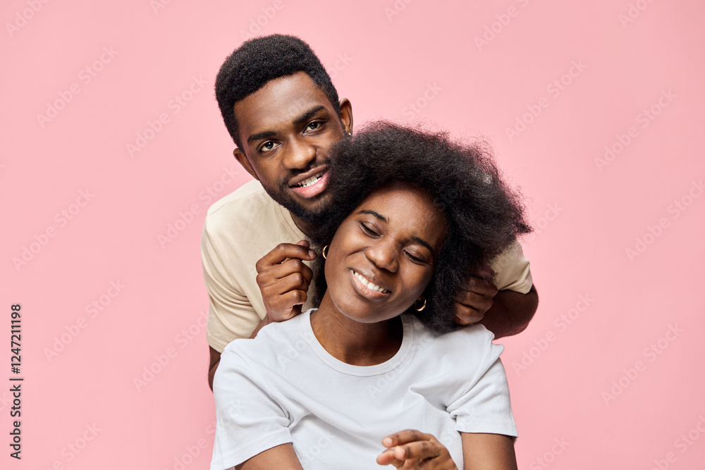 Obraz premium Happy couple enjoying quality time together, with joyful expressions against a pastel pink background, showcasing love and connection in a modern setting