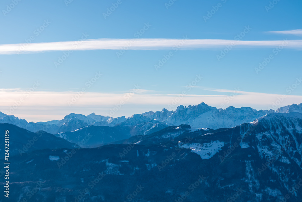 Fototapeta premium Snow-capped peaks of majestic Julian Alps seen from mountain peak Tscheckelnock, Carinthia, Austria. Dramatic mountainous range. Winter wonderland landscape. Wilderness, Austrian Alps. Clear blue sky