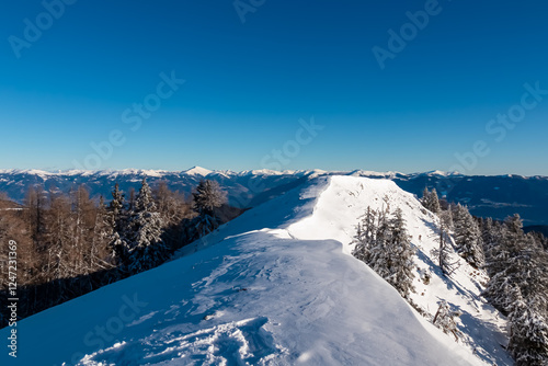 Panoramic view from summit of Tschekelnock with view of snow capped mountain peak in Nocky Mountains, Carinthia, Austria. Nockberge Biosphere Reserve in winter wonderland landscape. Austrian Alps photo