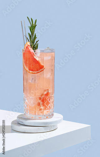 Refreshing mocktail with grapefruit, rosemary and ice in a glass on a blue background with shadow. photo