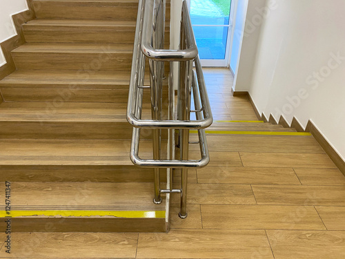 Modern staircase with metal multi-level handrails for adults and children. First and last steps marked with yellow warning stripe. Yellow lines at the edge of difference level. Concern for safety. photo