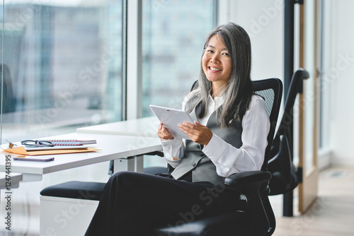 Smiling mature Asian business woman manager executive, happy middle aged businesswoman entrepreneur, 50 years old professional hr holding tablet looking at camera sitting in office at work. Portrait. Free Download Smiling mature Asian business woman manager executive, happy middle aged businesswoman entrepreneur, 50 years old professional hr holding tablet looking at camera sitting in office at work. Portrait. - GFXLoad
