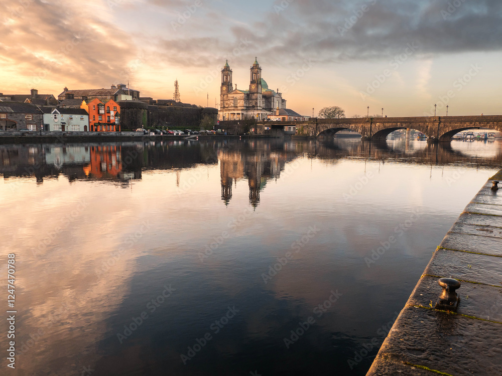 Fototapeta premium View on Riverside area of Athlone city, Ireland. Old town with long history and educational, shopping and industrial center. Church of Saints Peter and Paul in the background and town bridge