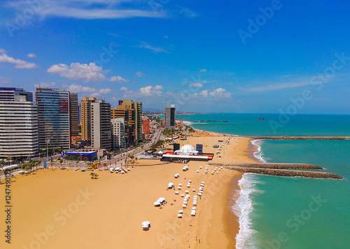 Above view of Iracema beach in Fortaleza, Ceara, Brazil. Golden sand with umbrellas and skyscrapers in the background.