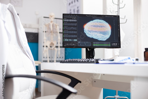 Unoccupied desk with computer screen displaying brain imaging data in doctors office. Modern pc monitor showing radiology results of human head highlighting use of advanced technology in hospital.