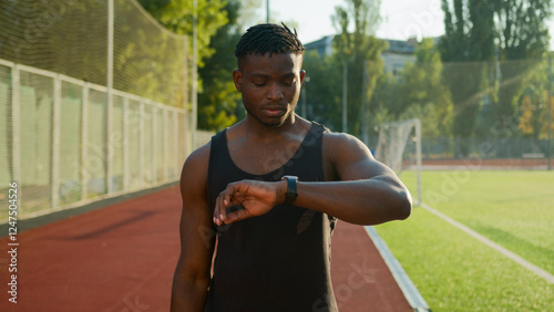 African American man runner jogger athlete muscular sportsman training outdoors athletic ethnic guy using smart band checking neck pulse heart rate result on smartwatch before running on sport stadium photo