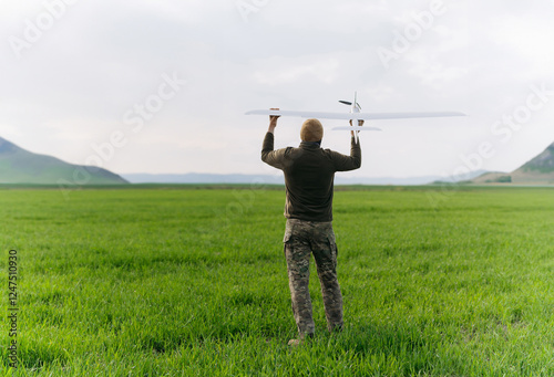 A soldier holds an unmanned aerial vehicle in his hands. A soldier in camouflage is recording a drone.