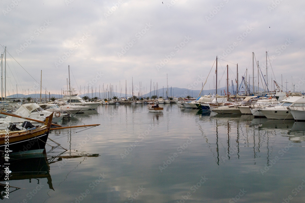 Fototapeta premium boats in the harbor, Pleasure boats in the port of Alghero. with the Capo Caccia promontory in the background Alghero, Sardinia, Italy.