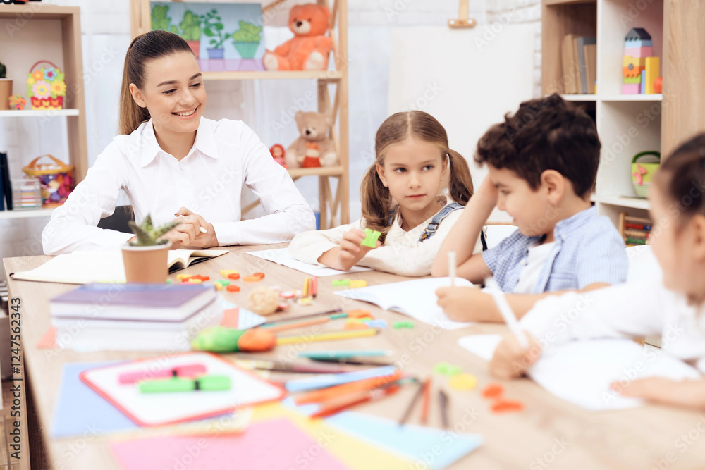 Fototapeta premium Children study letters in class at school. They have a lesson. An adult teacher helps them.