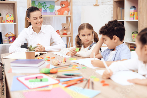 Children study letters in class at school. They have a lesson. An adult teacher helps them.