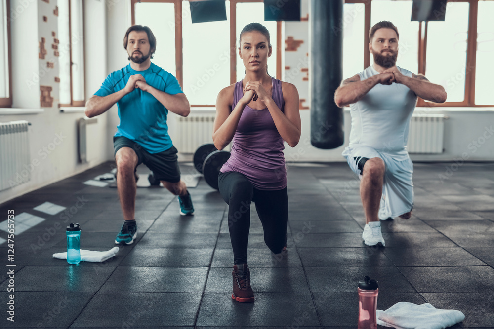 Fototapeta premium Girl And Two Guys Doing Lunge Exercises In Gym. Training Day. Fitness Club. Healthy Lifestyle. Powerful Athlete. Active Holidays. Crossfit Concept. Comfortable Sportswear. Legs Stretching.